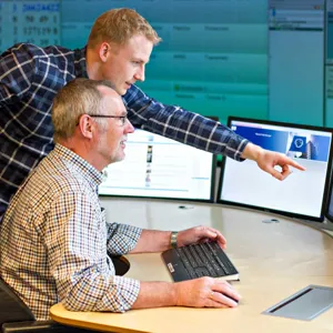 To menn som ser på en dataskjerm. Foto.